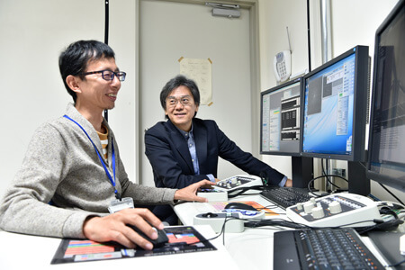 別室からクライオ電子顕微鏡を操作する加藤助教（左）と難波教授