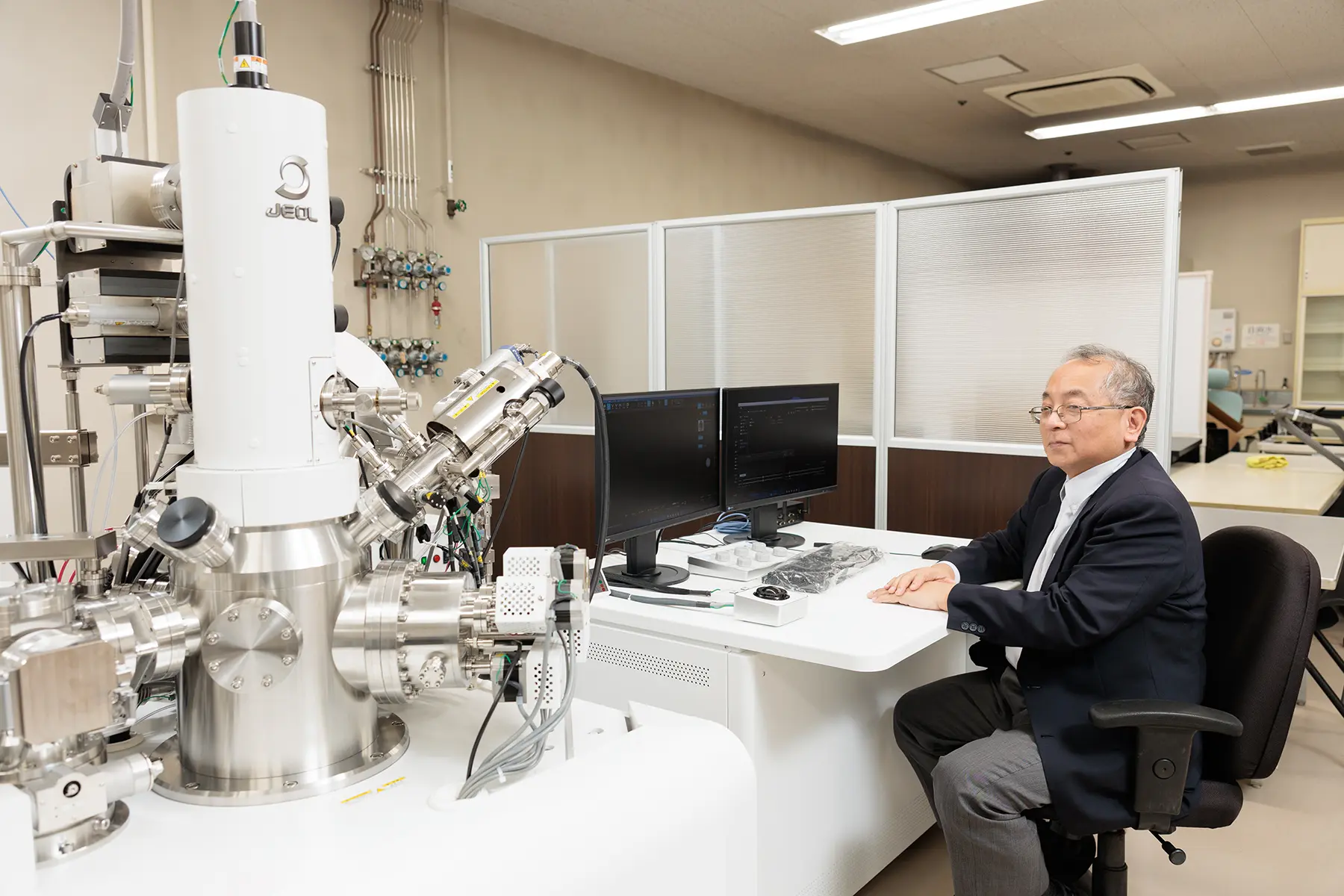 エネルギーフィルター走査電子顕微鏡の前に座る森茂生教授